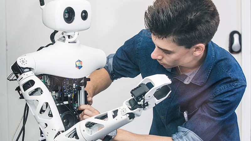 A young innovator with a humanoid robot, working at the X FAB Prototyping space at École Polytechnique.